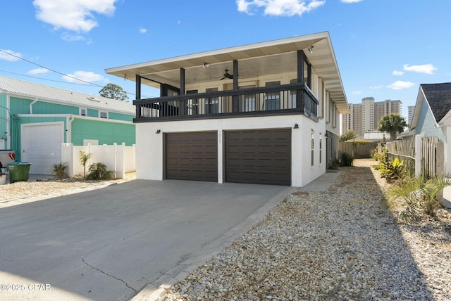 view of front facade featuring a garage, concrete driveway, a balcony, ceiling fan, and stucco siding