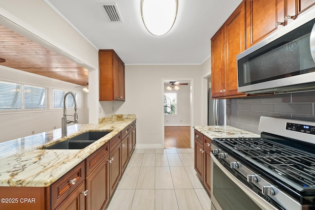 kitchen featuring sink, tasteful backsplash, light tile patterned floors, light stone countertops, and stainless steel appliances