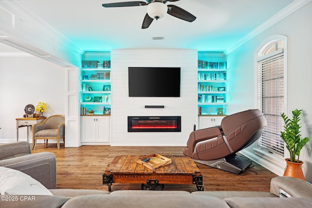 living room featuring crown molding, a large fireplace, hardwood / wood-style floors, and built in features