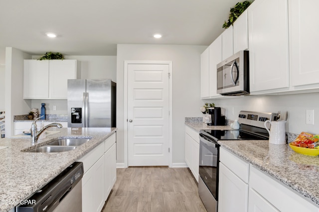 kitchen featuring light wood-type flooring, appliances with stainless steel finishes, white cabinets, and a sink