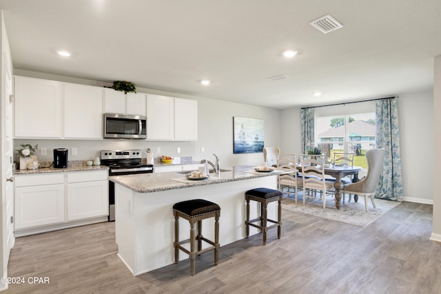 kitchen with appliances with stainless steel finishes, light wood-type flooring, and white cabinetry