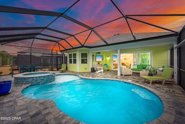 pool at dusk with an in ground hot tub, a patio, an outdoor hangout area, and glass enclosure