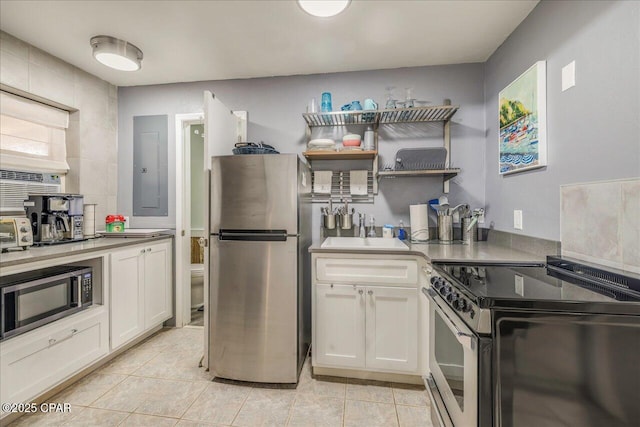 kitchen featuring sink, white cabinetry, light tile patterned floors, electric panel, and stainless steel appliances