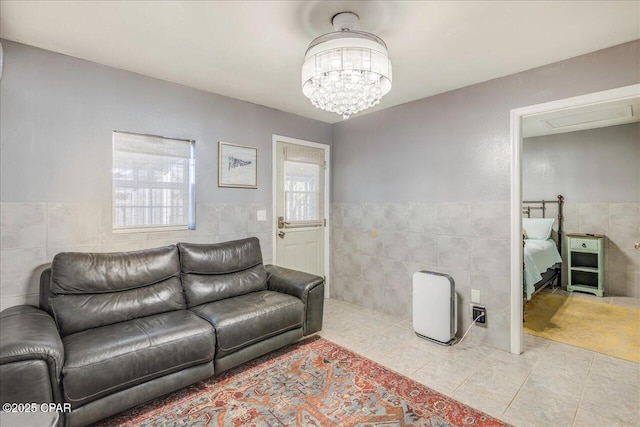 living room featuring tile walls, light tile patterned floors, and an inviting chandelier