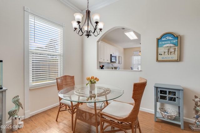 dining space featuring light wood-type flooring, crown molding, and a notable chandelier