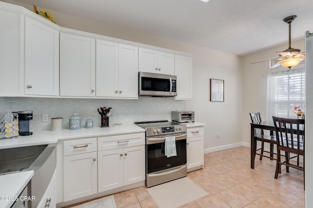 kitchen with appliances with stainless steel finishes, white cabinetry, tasteful backsplash, hanging light fixtures, and light tile patterned floors