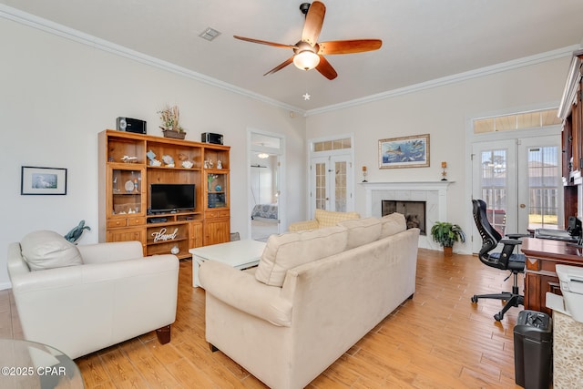 living room with french doors, light wood-type flooring, ceiling fan, a tile fireplace, and crown molding