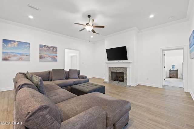 living area with light wood-type flooring, visible vents, and crown molding