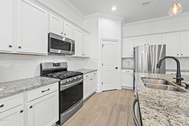 kitchen with a sink, visible vents, white cabinets, appliances with stainless steel finishes, and crown molding