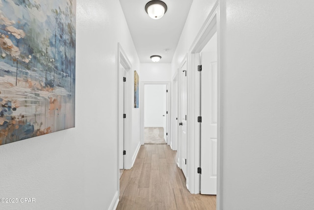 hall with light wood-style flooring and baseboards