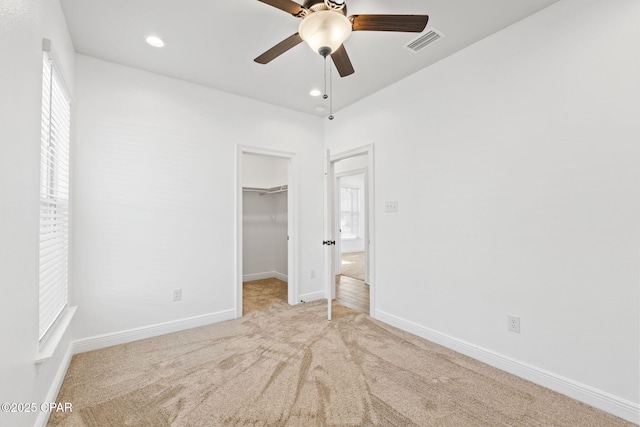 unfurnished bedroom with a spacious closet, carpet flooring, visible vents, and baseboards