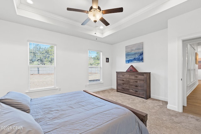 bedroom with carpet, baseboards, a raised ceiling, and ornamental molding