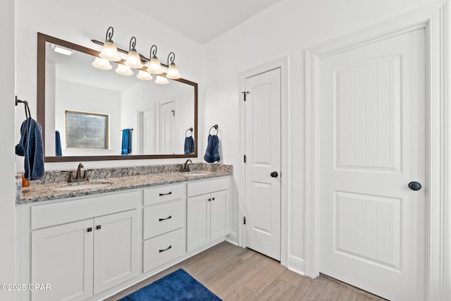 bathroom with double vanity, a sink, and wood finished floors