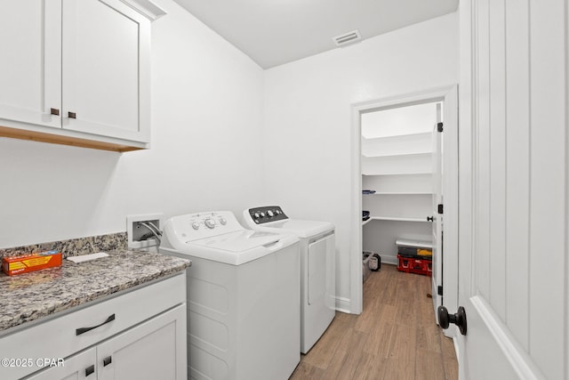 laundry room featuring visible vents, light wood finished floors, independent washer and dryer, and cabinet space