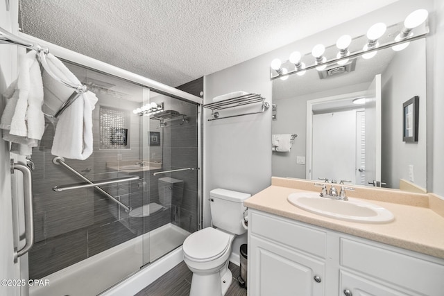 bathroom featuring walk in shower, vanity, toilet, and a textured ceiling