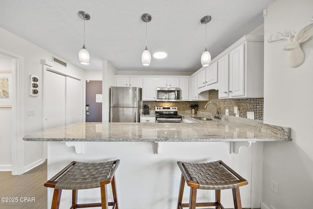 kitchen featuring appliances with stainless steel finishes, sink, white cabinets, and kitchen peninsula