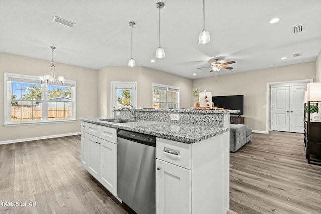 kitchen featuring sink, white cabinets, stainless steel dishwasher, light stone countertops, and a center island with sink