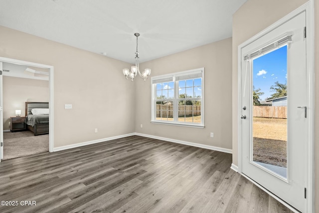 unfurnished dining area with wood-type flooring and a notable chandelier