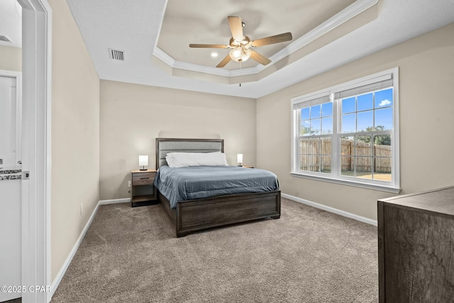 carpeted bedroom featuring ceiling fan, ornamental molding, and a tray ceiling