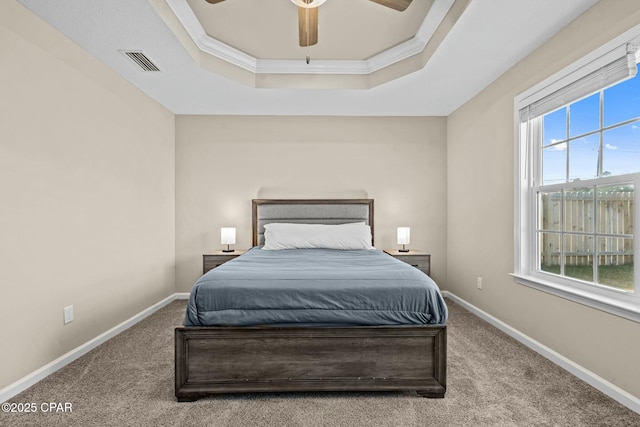 carpeted bedroom featuring crown molding, a raised ceiling, and ceiling fan