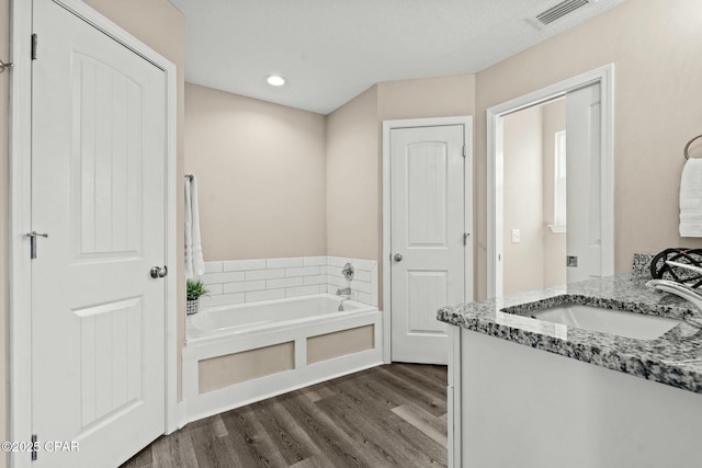 bathroom featuring hardwood / wood-style floors, vanity, and a washtub