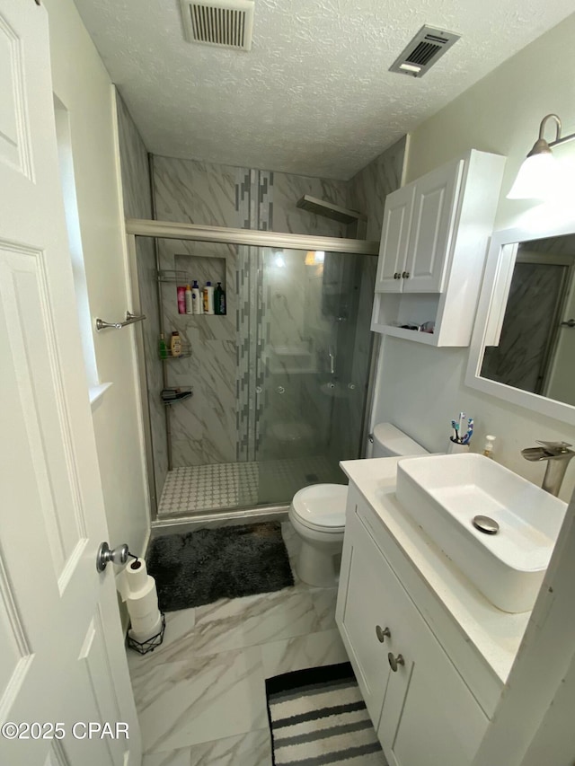 bathroom featuring vanity, a shower with shower door, a textured ceiling, and toilet