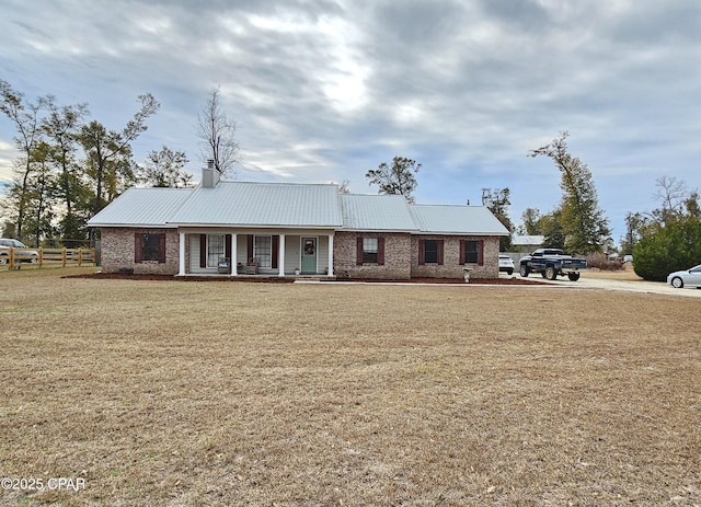 ranch-style house featuring covered porch and a front lawn