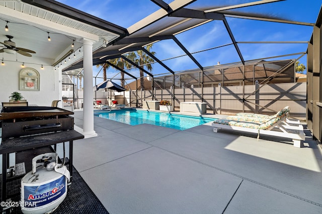 view of swimming pool with ceiling fan, a patio area, and glass enclosure