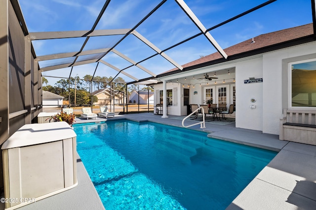 view of swimming pool featuring french doors, ceiling fan, glass enclosure, and a patio area