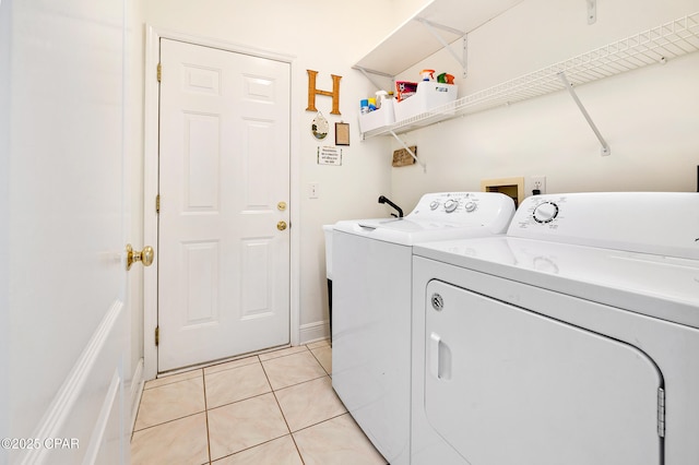 clothes washing area with light tile patterned flooring and washer and dryer