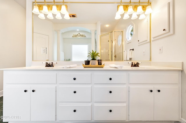 bathroom featuring an enclosed shower, vanity, and decorative columns