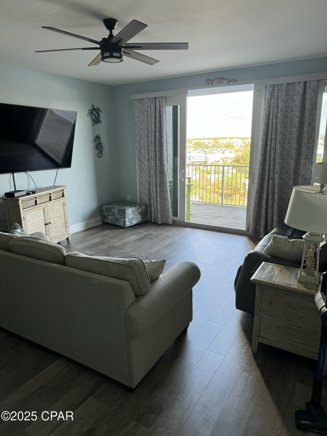 living area featuring dark wood-style floors, baseboards, and a ceiling fan