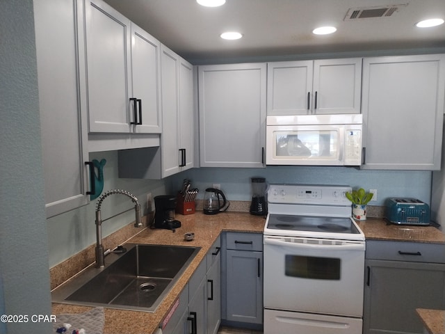 kitchen featuring white appliances, visible vents, white cabinets, a sink, and recessed lighting