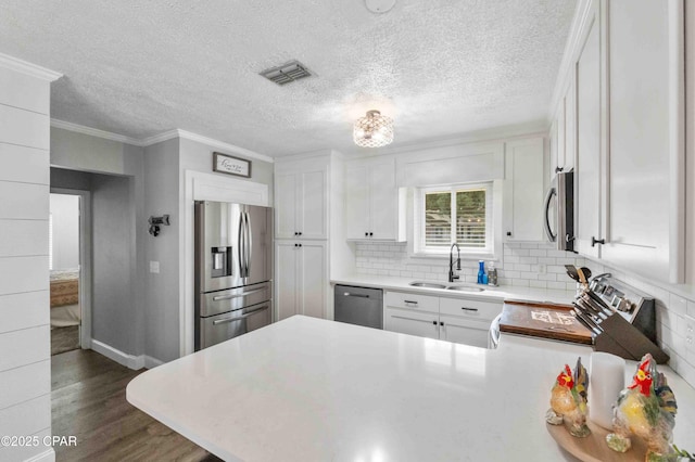 kitchen featuring sink, ornamental molding, dark hardwood / wood-style floors, stainless steel appliances, and white cabinets