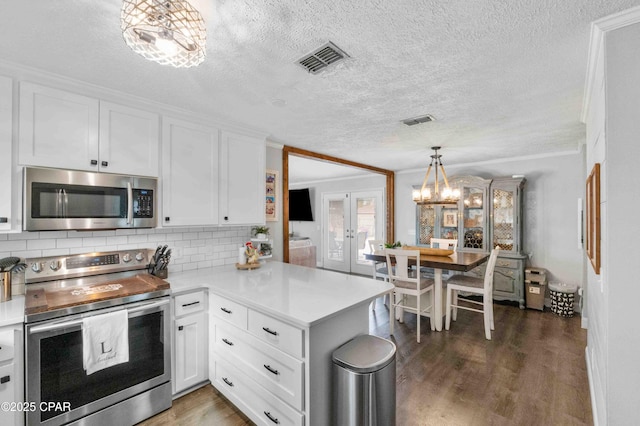 kitchen with decorative light fixtures, kitchen peninsula, white cabinets, and appliances with stainless steel finishes