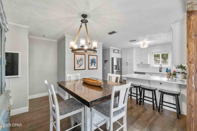 dining space with crown molding, an inviting chandelier, dark wood-type flooring, and a textured ceiling