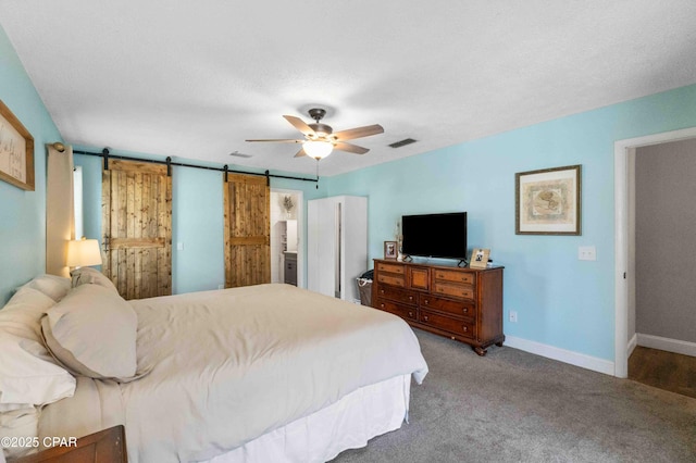 carpeted bedroom with ceiling fan, a barn door, and a textured ceiling