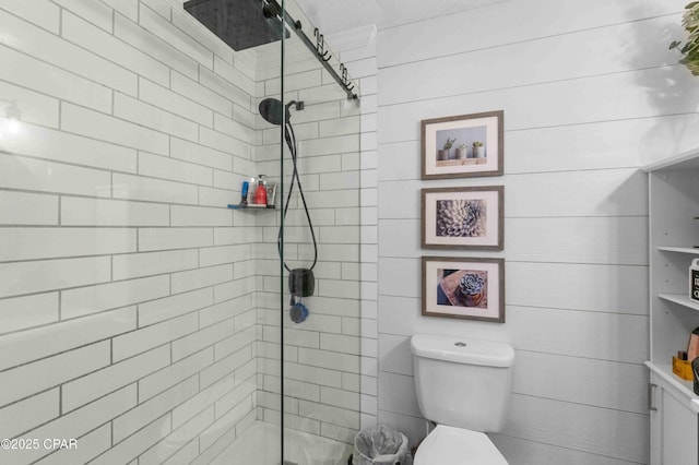 bathroom with a tile shower and toilet