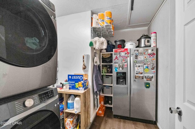 kitchen with stainless steel refrigerator with ice dispenser, stacked washer and dryer, wood-type flooring, and a textured ceiling