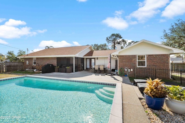 rear view of property featuring a sunroom, a fenced in pool, and a patio