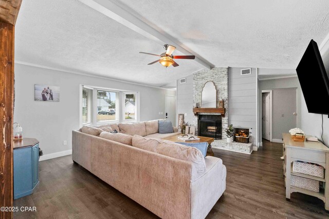 living room with ceiling fan, vaulted ceiling with beams, dark hardwood / wood-style floors, a large fireplace, and a textured ceiling