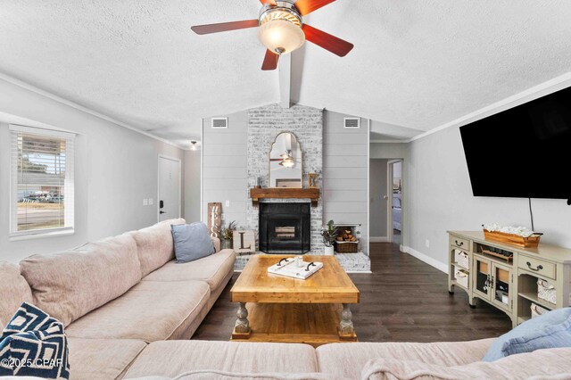 living room with ceiling fan, dark hardwood / wood-style flooring, a brick fireplace, and a textured ceiling