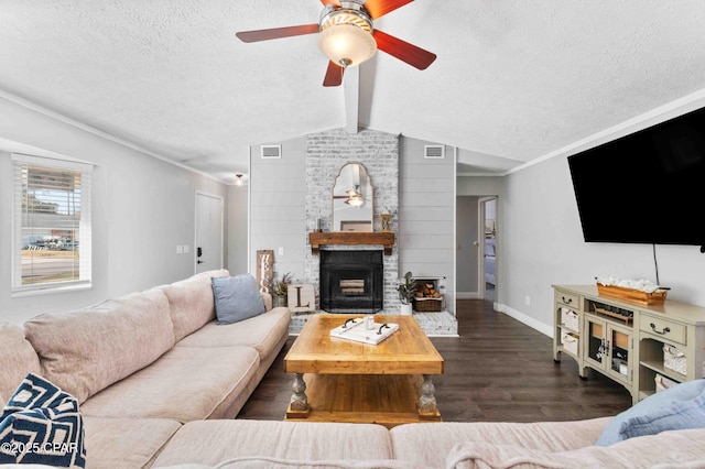 living room featuring dark wood-type flooring, ceiling fan, a fireplace, lofted ceiling with beams, and a textured ceiling