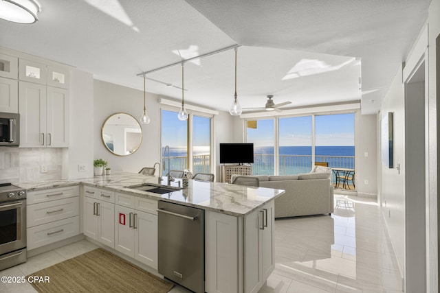 kitchen with tasteful backsplash, white cabinets, sink, kitchen peninsula, and stainless steel appliances