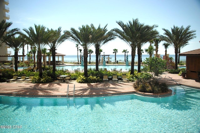 view of swimming pool featuring a patio and a water view