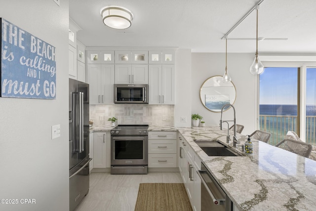 kitchen featuring white cabinetry, stainless steel appliances, tasteful backsplash, sink, and a water view