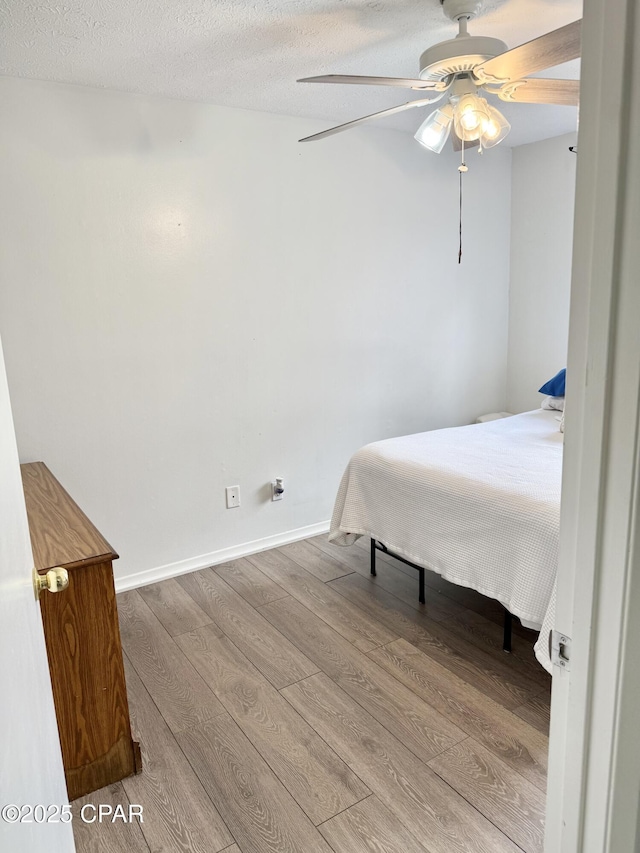 bedroom with light hardwood / wood-style floors, a textured ceiling, and ceiling fan