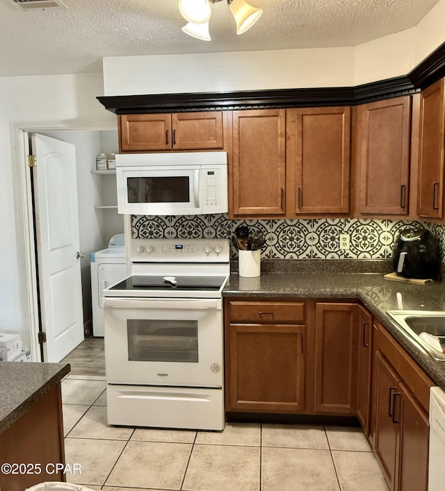 kitchen with sink, white appliances, light tile patterned floors, and a textured ceiling