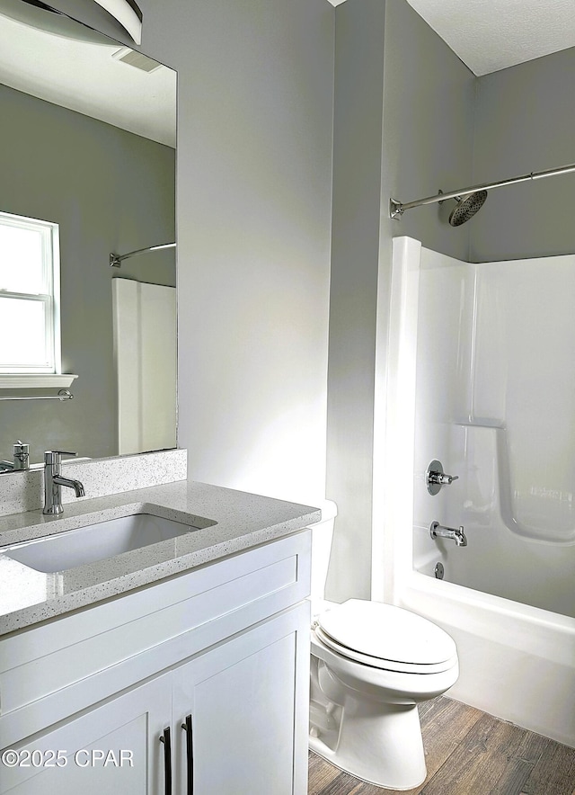 full bathroom featuring vanity,  shower combination, toilet, and hardwood / wood-style flooring