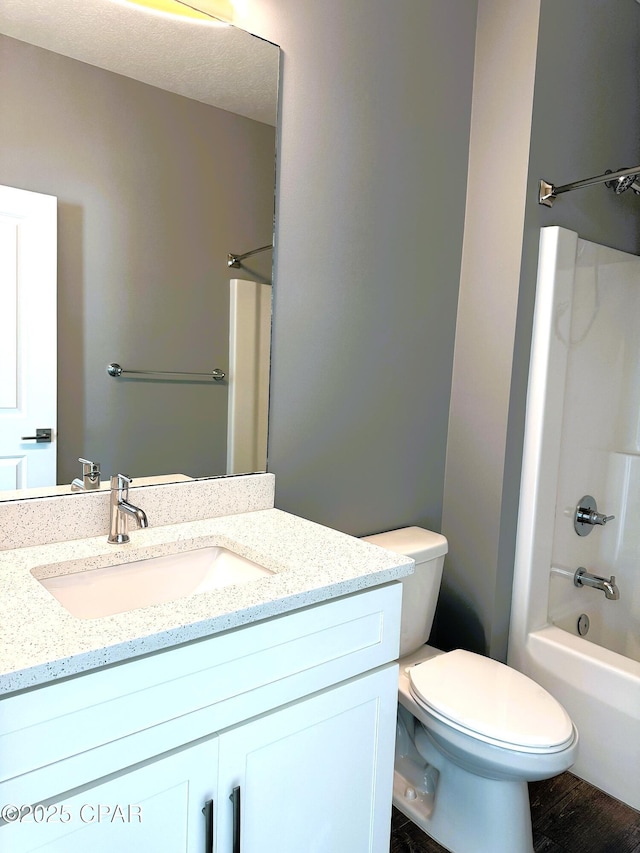 full bathroom featuring hardwood / wood-style flooring, toilet, shower / bathing tub combination, and vanity